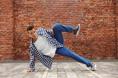 Photo of Man dancing hip hop near brick wall outdoors