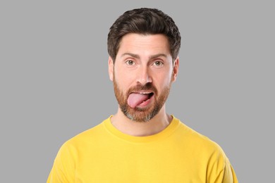 Man showing his tongue on gray background