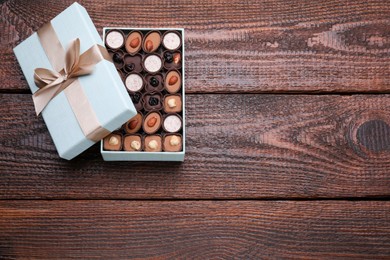 Photo of Open box of delicious chocolate candies on wooden table, top view. Space for text