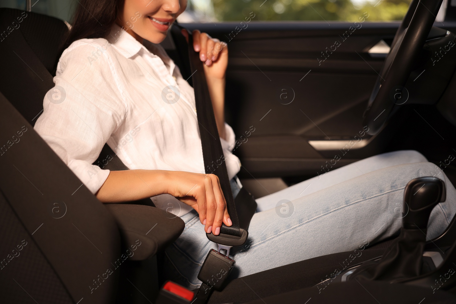 Photo of Woman fastening safety seat belt in car, closeup