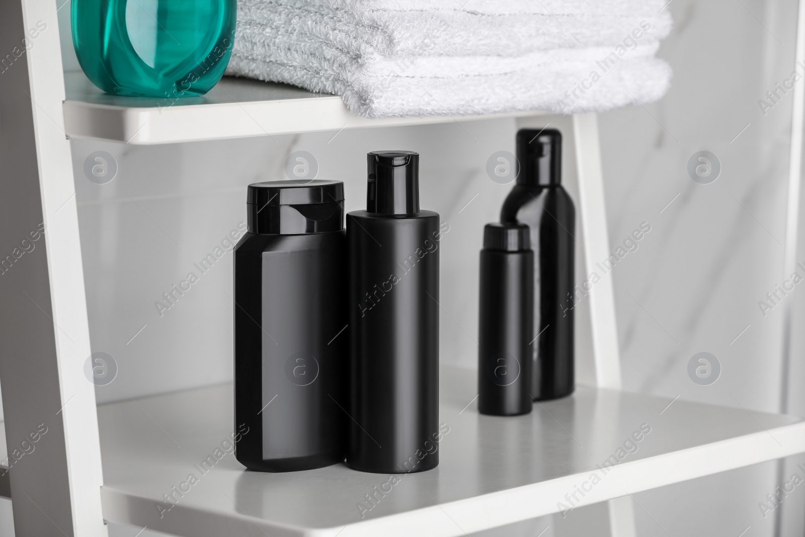 Photo of Stack of towels, shampoo and other toiletries on shelves in bathroom