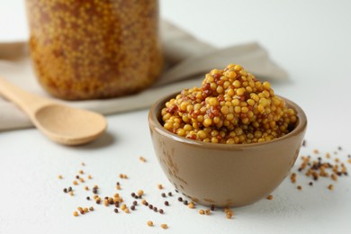 Photo of Fresh whole grain mustard in bowl and dry seeds on white table. Space for text