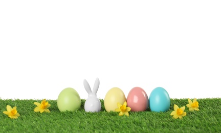 Photo of Dyed Easter eggs and bunny ears on green grass against white background