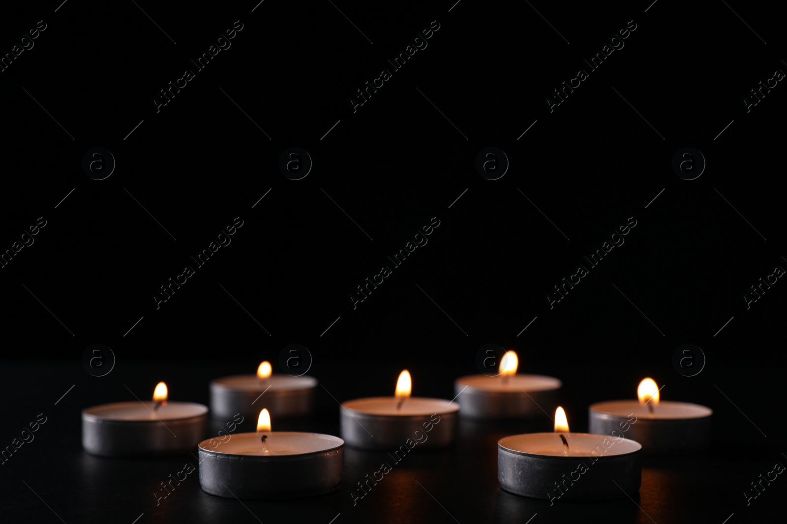 Photo of Burning candles on black background, space for text. Holocaust memory day