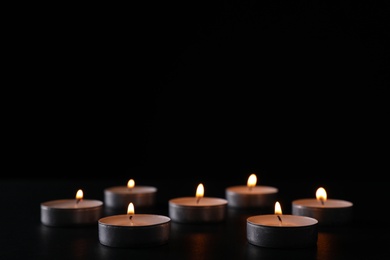 Photo of Burning candles on black background, space for text. Holocaust memory day