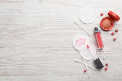 Dirty cotton pads, swabs and cosmetic products on white wooden background, flat lay. Space for text