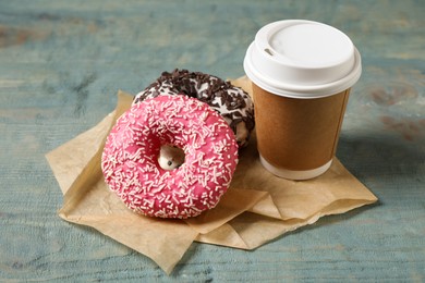 Photo of Yummy donuts with sprinkles and paper cup on wooden table