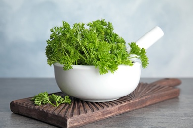 Mortar with fresh green parsley on table