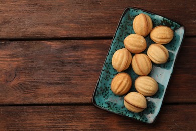 Photo of Delicious nut shaped cookies with boiled condensed milk on wooden table, top view. Space for text