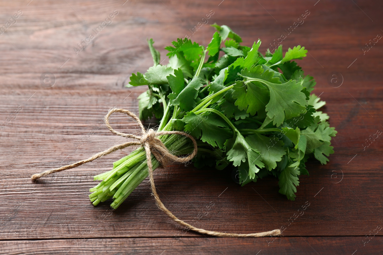 Photo of Bunch of fresh coriander on wooden table