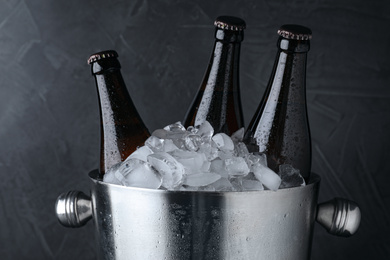 Metal bucket with beer and ice cubes on black background, closeup