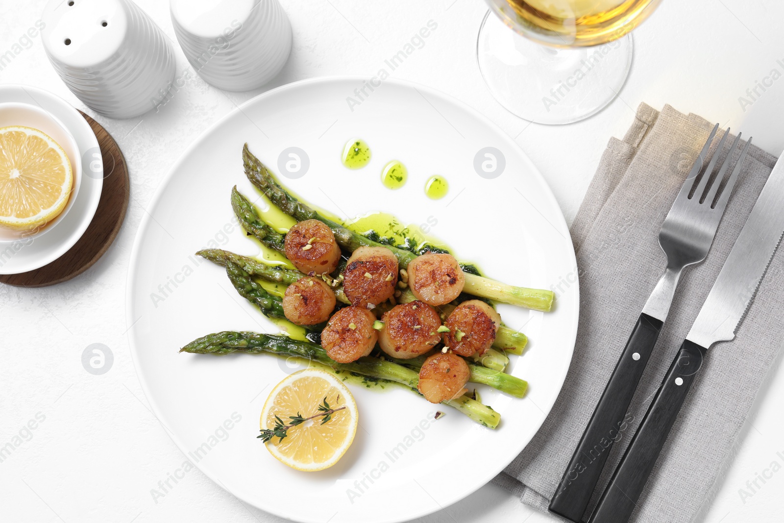 Photo of Delicious fried scallops with asparagus, lemon and thyme served on white table, flat lay