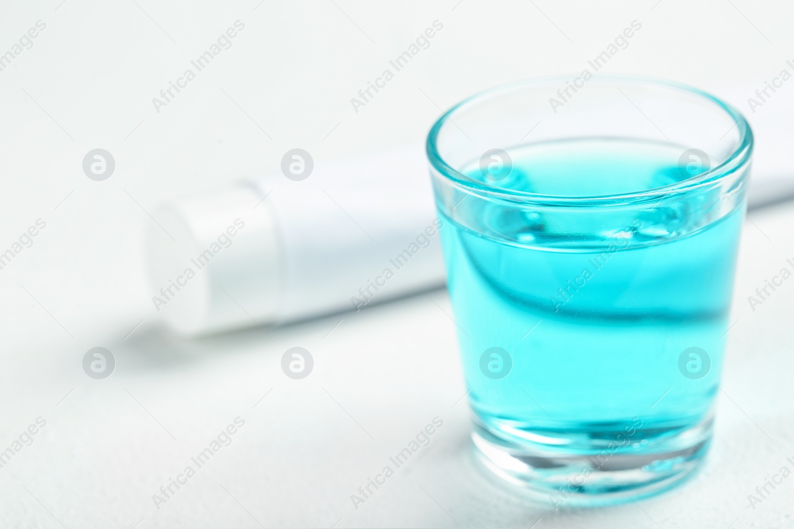 Photo of Glass with mouthwash on light background. Teeth care