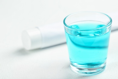 Glass with mouthwash on light background. Teeth care