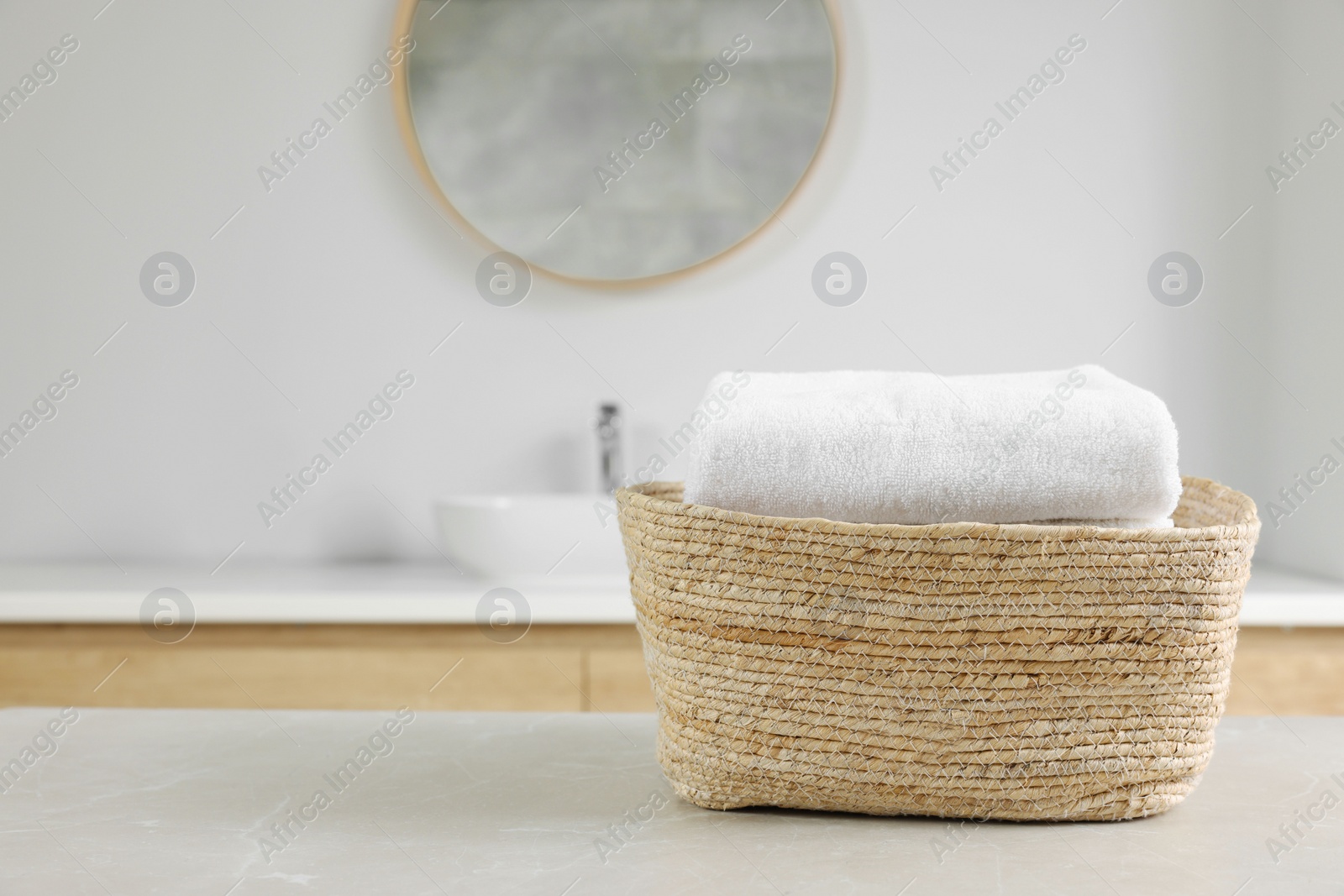 Photo of Wicker basket with white towels on table in bathroom. Space for text