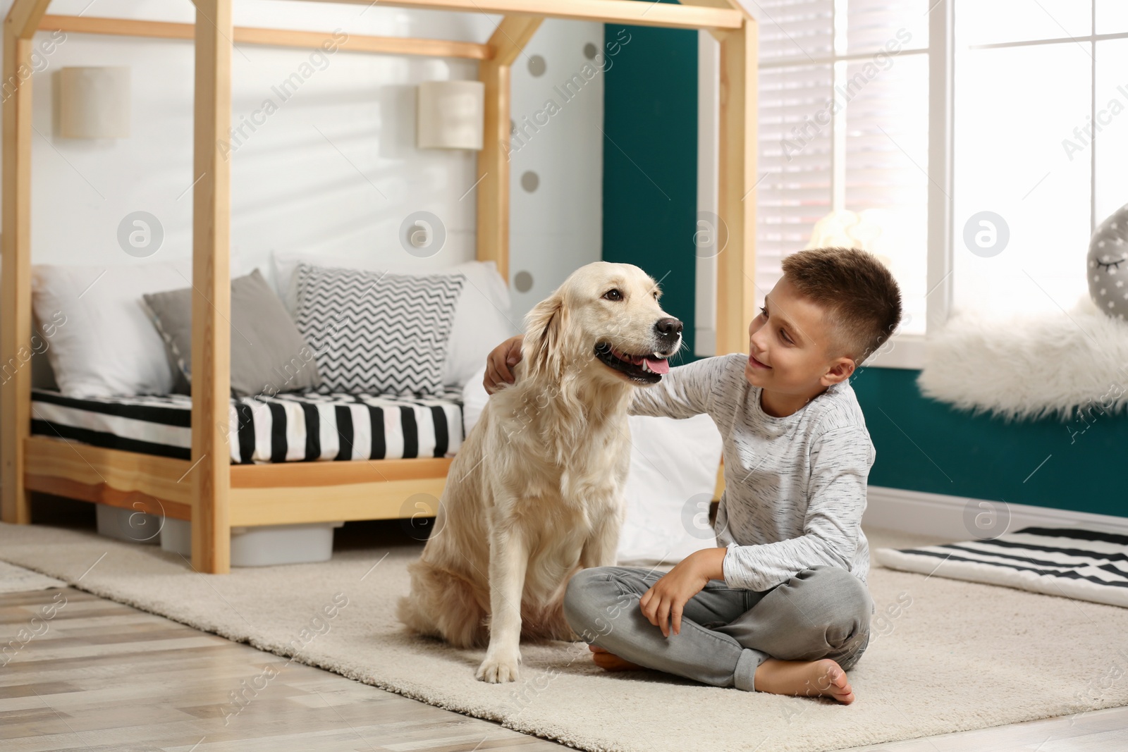 Photo of Little boy with his dog in stylish bedroom interior