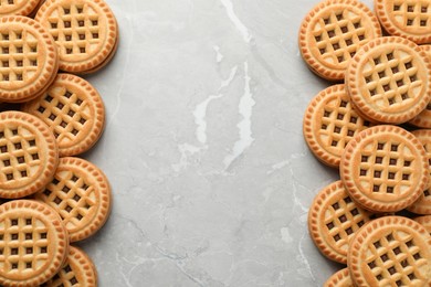 Tasty sandwich cookies with cream on grey table, flat lay. Space for text