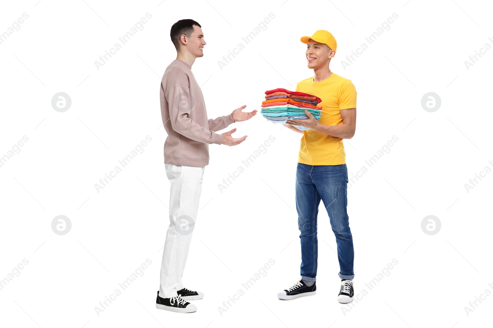 Image of Dry-cleaning delivery. Courier giving folded clothes to man on white background