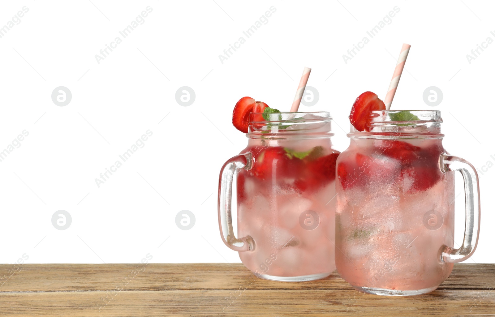 Photo of Mason jars with strawberry refreshing drink on wooden table against white background