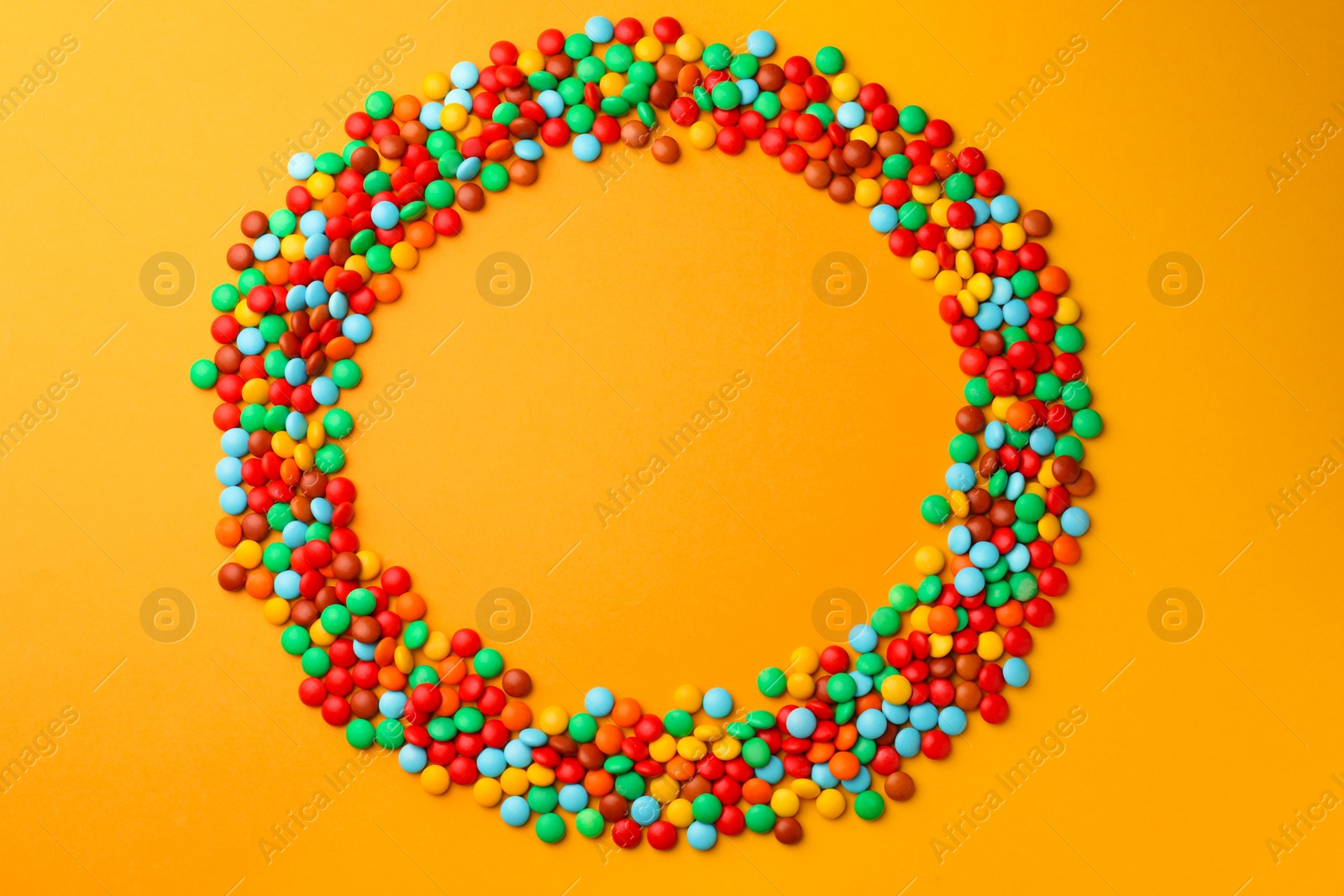 Photo of Frame of tasty colorful candies on yellow background, flat lay. Space for text