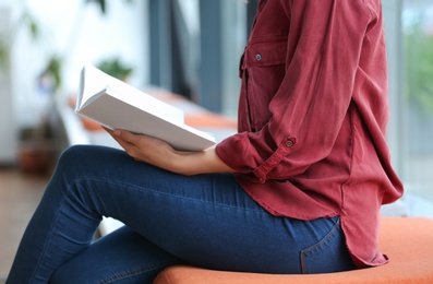 Photo of Young woman reading book in library, closeup