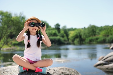Photo of Little girl with binoculars outdoors. Summer camp