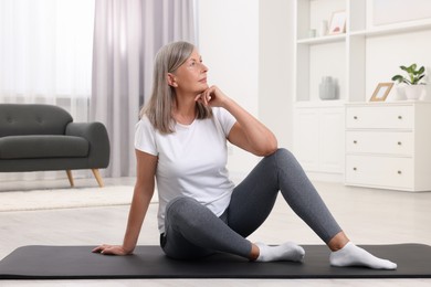 Photo of Senior woman sitting on mat at home. Yoga practice