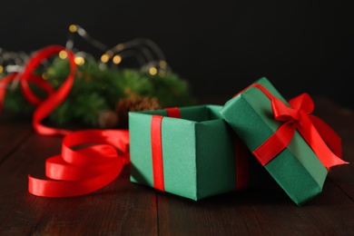 Green Christmas gift box with red bow on wooden table