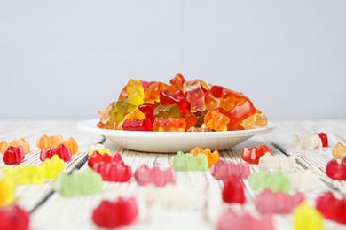 Photo of Plate with delicious jelly bears on wooden table