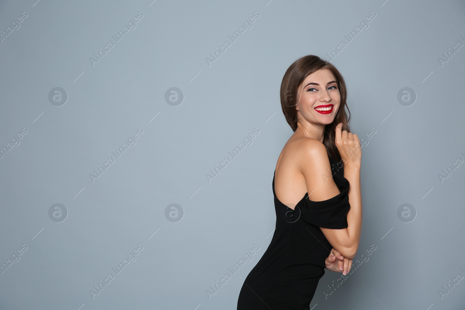 Photo of Happy woman in black dress on grey background, space for text. Christmas party