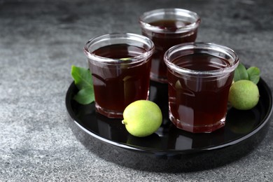 Photo of Delicious liqueur and green walnuts on grey table. Space for text