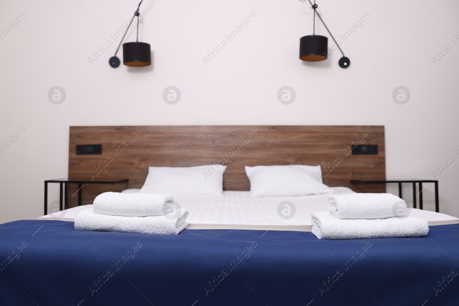 Photo of Clean folded towels on bed in hotel room