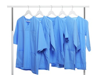 Light blue medical uniforms on rack against white background