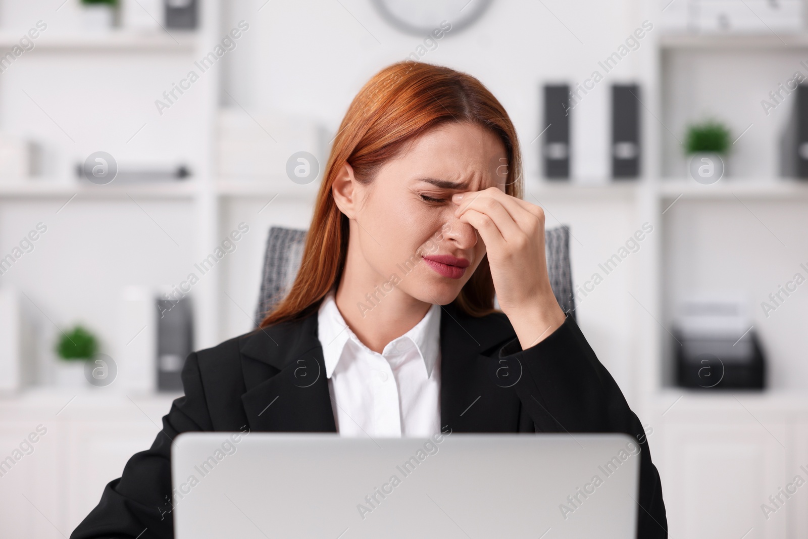 Photo of Woman suffering from headache at workplace in office