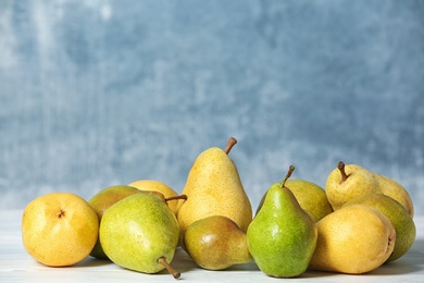 Fresh ripe pears on table against color background. Space for text