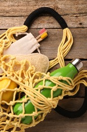 Photo of Net bag with different items on wooden table, top view. Conscious consumption