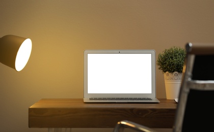 Photo of Laptop with blank screen on table indoors. Space for text