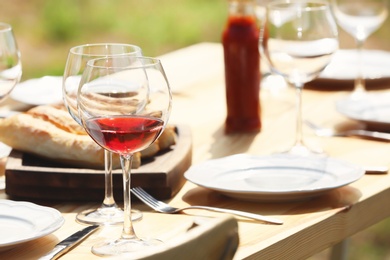 Photo of Wine glasses on table outdoors. Summer picnic