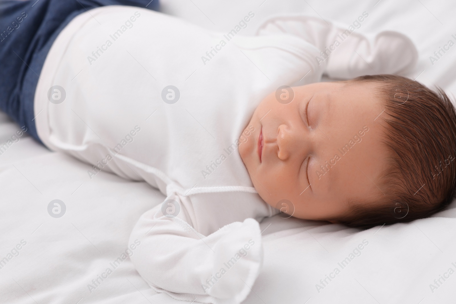 Photo of Cute newborn baby sleeping on white blanket, closeup