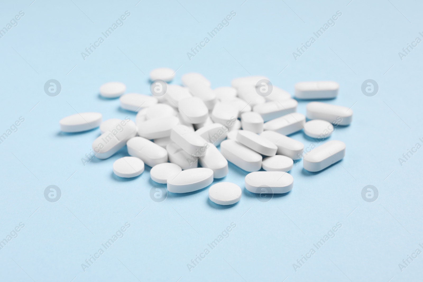 Photo of Pile of pills on light blue background