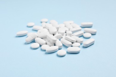Pile of pills on light blue background