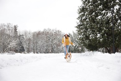 Woman with adorable Pembroke Welsh Corgi dog running in snowy park