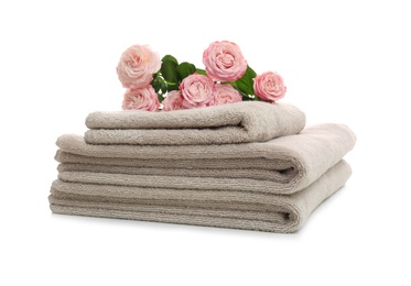 Stack of clean folded towels with flowers on white background