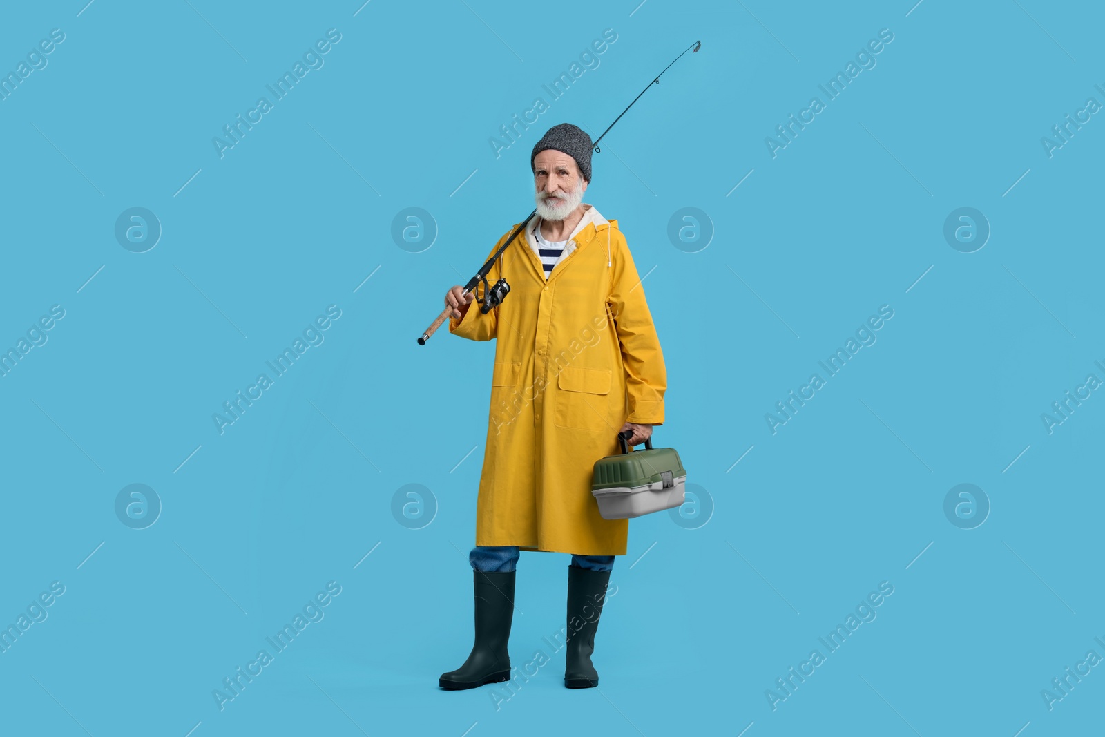 Photo of Fisherman with rod and tackle box on light blue background