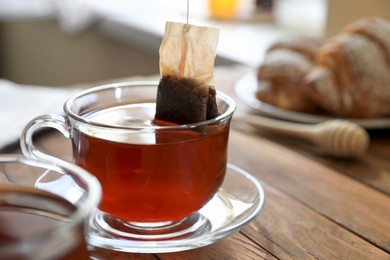 Photo of Taking tea bag out of cup on wooden table indoors, closeup. Space for text