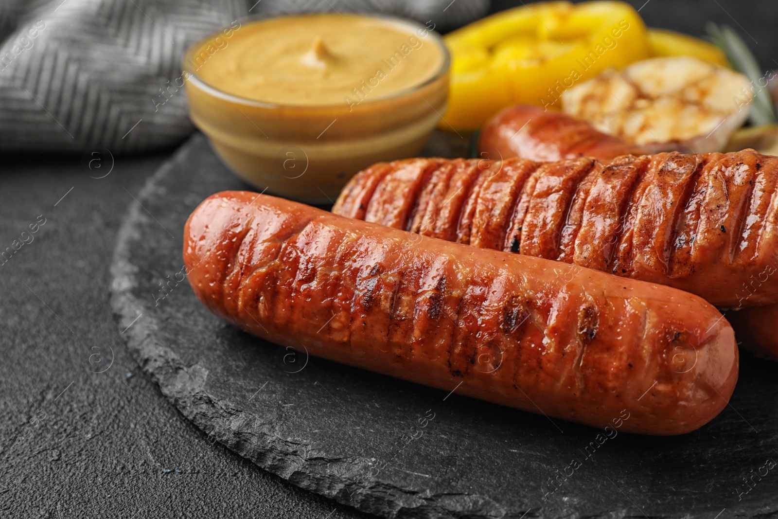 Photo of Delicious grilled sausages on black table, closeup. Barbecue food