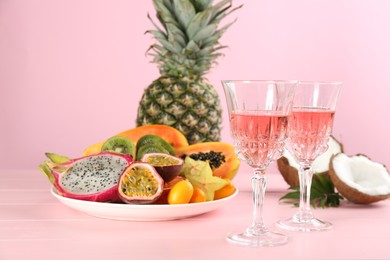 Delicious exotic fruits and wine on pink wooden table