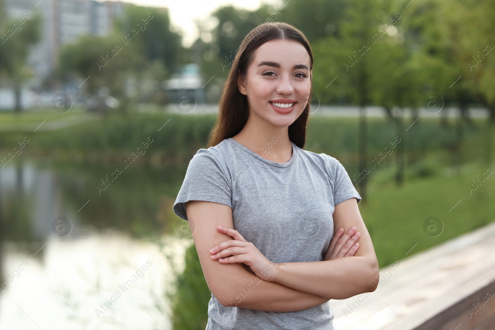 Photo of Portrait of beautiful woman with crossed arms outdoors. Attractive lady smiling and looking into camera. Space for text