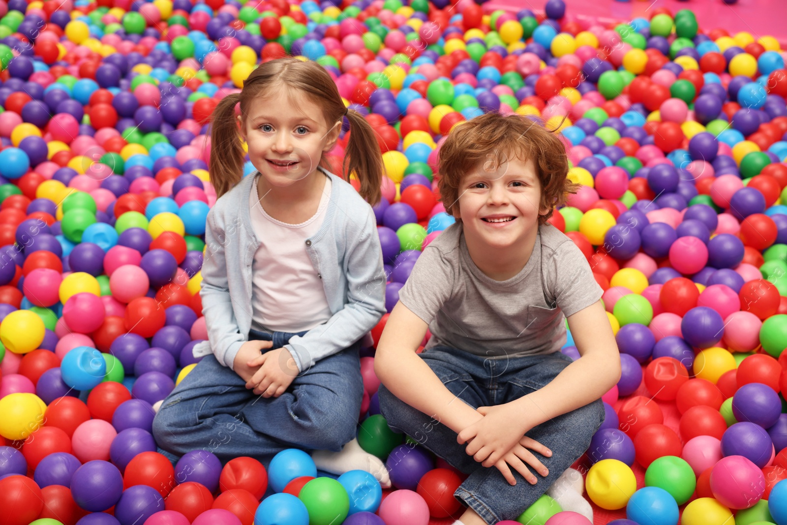Photo of Happy little kids sitting on colorful balls in ball pit