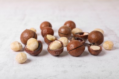 Photo of Delicious organic Macadamia nuts on white textured table, closeup
